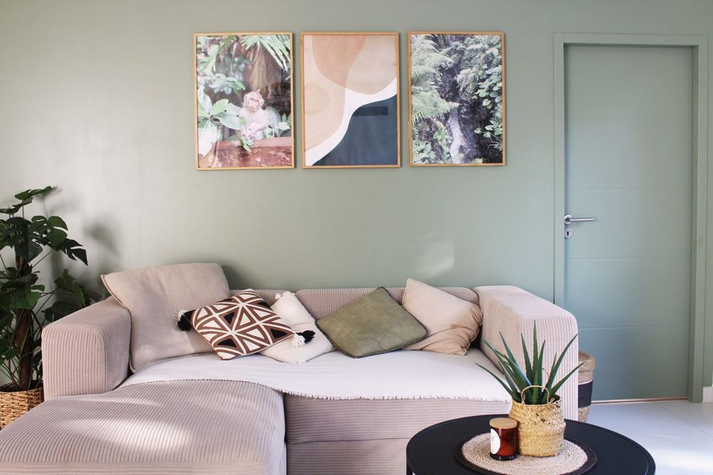 Salon avec mur vert sauge et cadres décoratifs